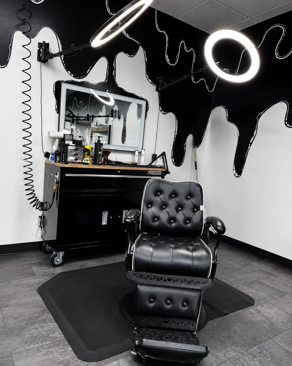 Damion's chair and station beneath the shop's black paint-drip mural